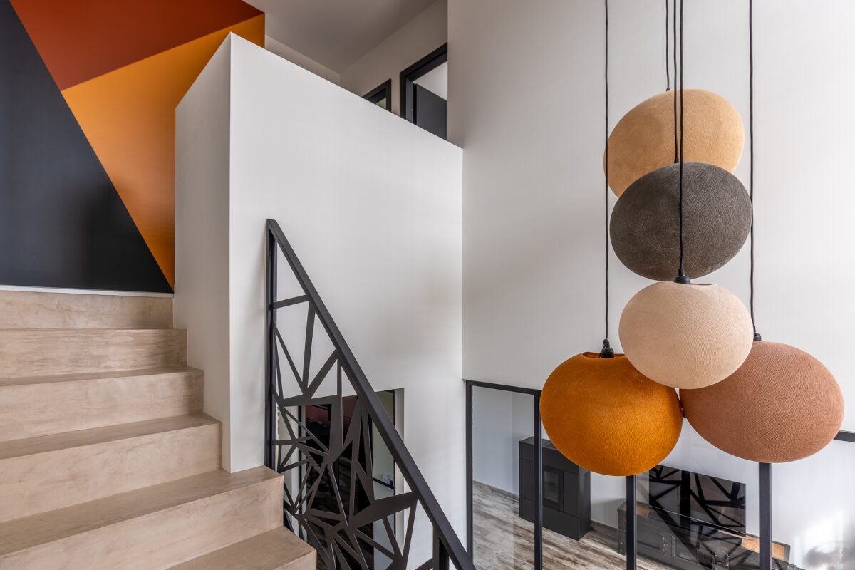 Escalier, mur ocre et suspensions en boules colorées