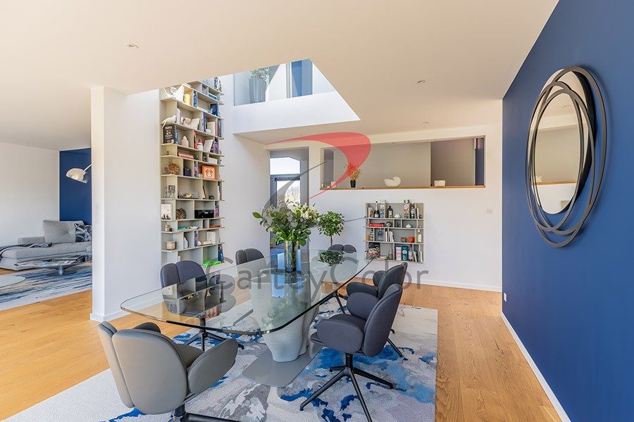 Salle à manger au mur bleu et miroir rond
