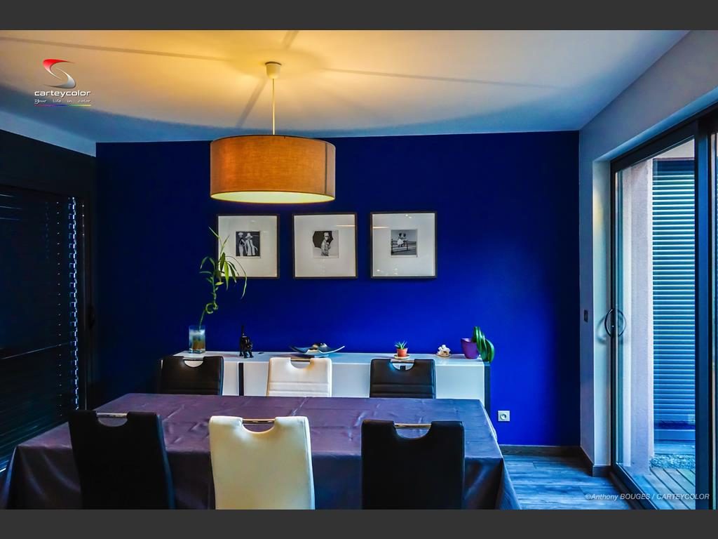 Salle à manger au mur bleu profond, cadres noir et blanc
